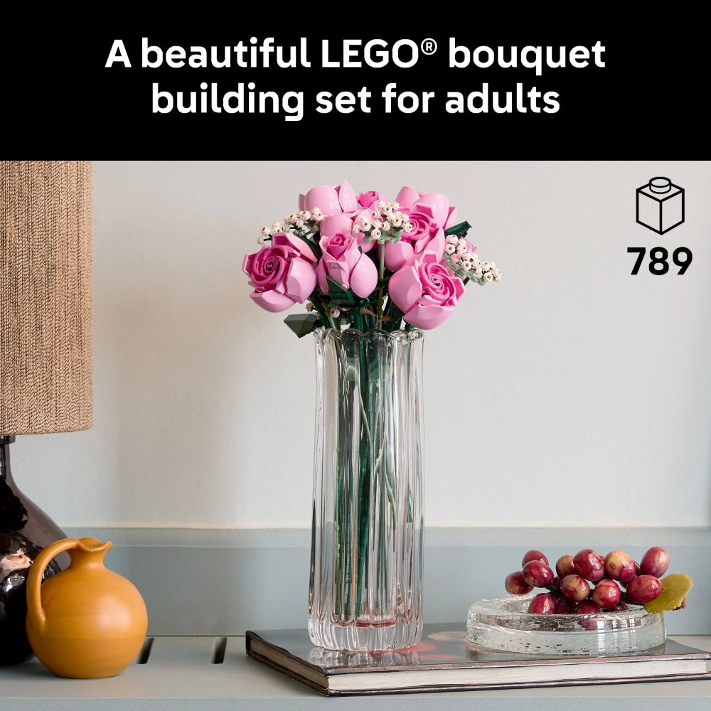 LEGO Bouquet building set featuring pink roses and white flowers in a clear glass vase, displayed on a styled surface with a yellow pitcher, grapes, and book, 789 pieces, adult building set