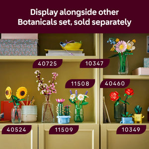 LEGO Flowering Cactus set 11509 displayed on yellow shelving alongside other botanical LEGO sets, featuring a pink flower bloom on a green cactus stem in a blue pot, surrounded by complementary floral arrangements in glass vases