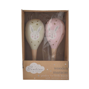 Bambino by Juliana wooden maracas set with two rabbit-shaped rattles, one cream with gold stars and one pink with mauve stars, featuring cute bunny faces with pink cheeks, displayed in cardboard packaging labeled perfect for little hands and curious minds