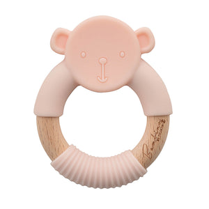 Pink monkey-shaped teething ring with wooden base on a white background