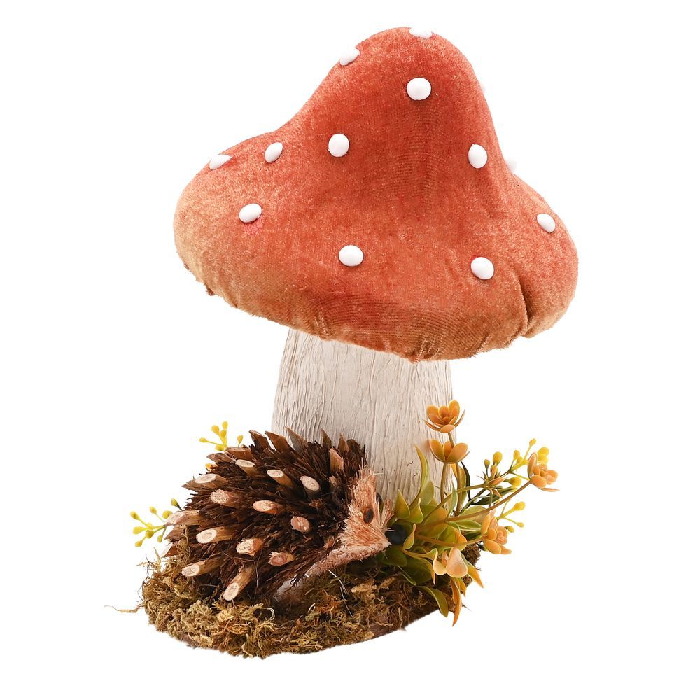 Handmade decorative ornament featuring a red and white spotted mushroom with cream stem above a brown hedgehog surrounded by moss, pinecone, and golden yellow flowers on white background