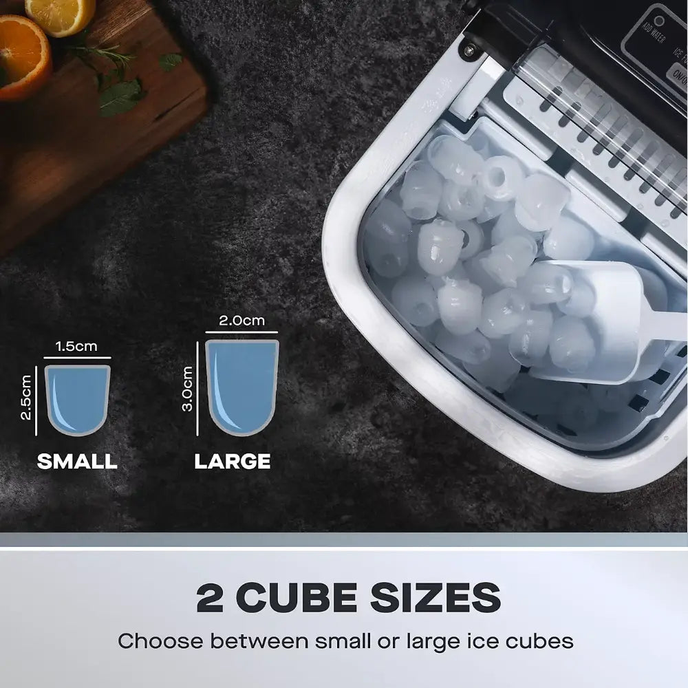 Daewoo portable ice cube maker machine in white stainless steel showing open top with ice cubes inside, alongside size comparison diagram displaying small ice cubes 1.5cm and large ice cubes 2.0cm, with fresh citrus fruits and cutting board in background on dark countertop