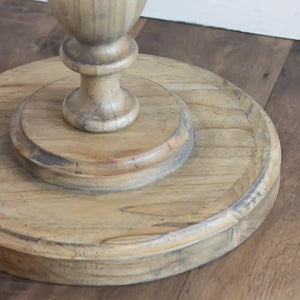 Tara Lane Round Pillar Side Table in natural wood with turned pedestal base, circular top and lower shelf, displayed on wooden floor
