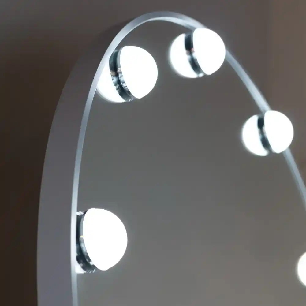White arched cheval mirror with LED bulb lights mounted on frame, showing four illuminated circular light fixtures against neutral background
