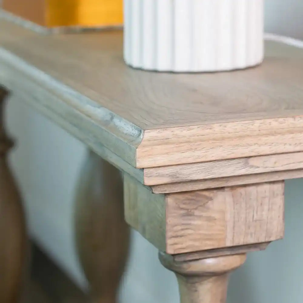 Close-up detail of Tara Lane Pillars Console Table showing natural wood top with turned wooden pillar leg and green-painted base, white ribbed ceramic pot in background