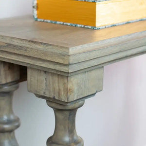 Tara Lane Pillars Console Table 120cm in Marwood finish showing natural wood top with turned pedestal legs and yellow decorative book displayed on surface