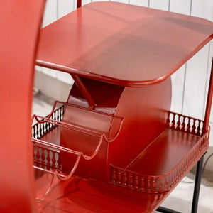 Red metal Vespa scooter-shaped wine rack with decorative railings and curved shelves, displayed against white brick background