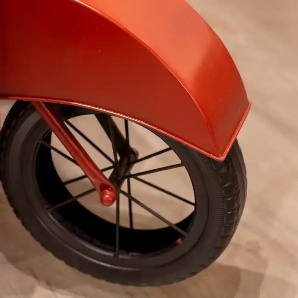 Red Vespa scooter-shaped wine rack with black wheel and spoke details, front angled view showing tire and fender design