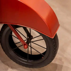 Red Vespa scooter-shaped wine rack with black wheel and spoke details, front angled view showing tire and fender design