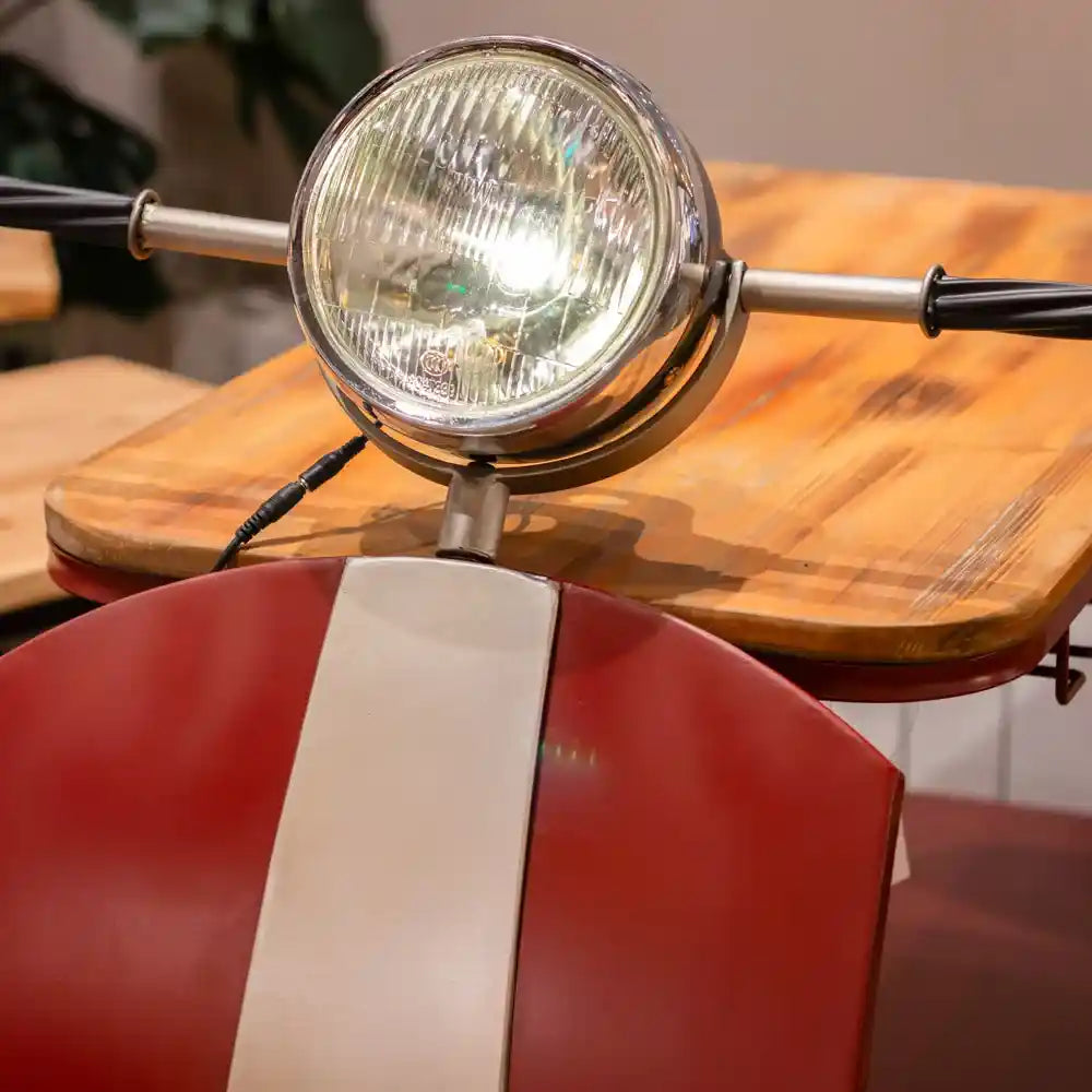 Decorative Vespa scooter wine rack in red and cream with chrome headlight and wooden seat, displayed indoors on wooden surface