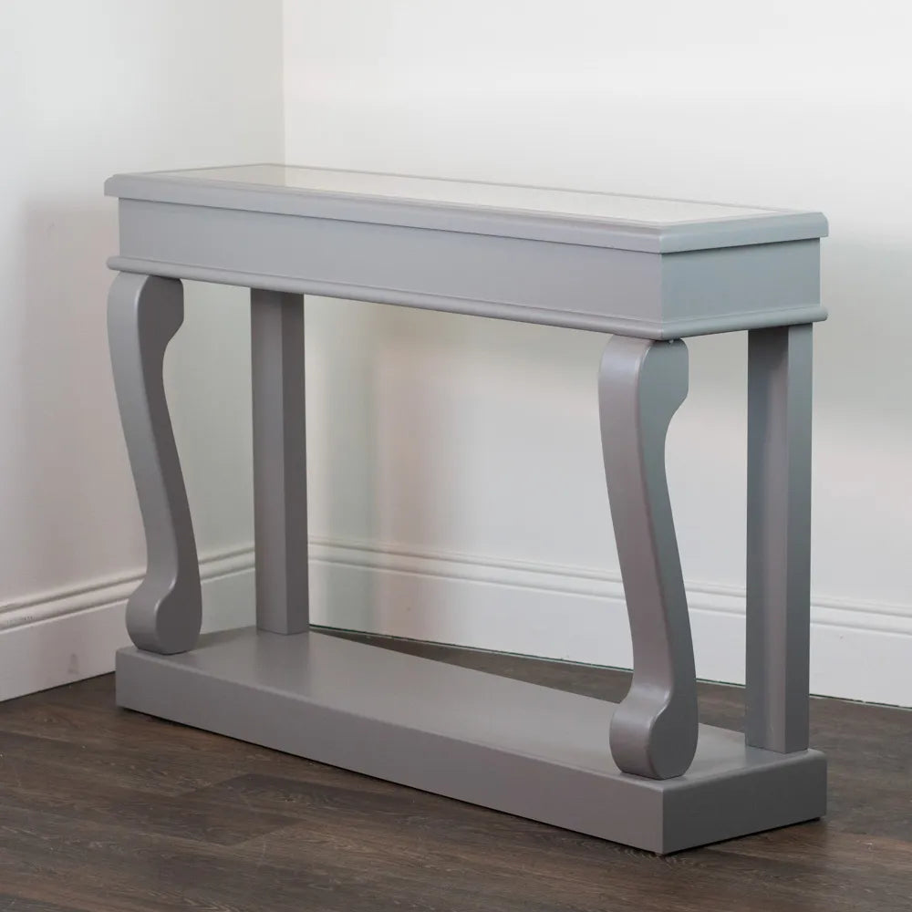 Mink grey Tara Lane Scroll Console Table with antique mirror top, featuring curved bracket legs and straight supports, 120cm width, displayed against white wall and dark wood flooring