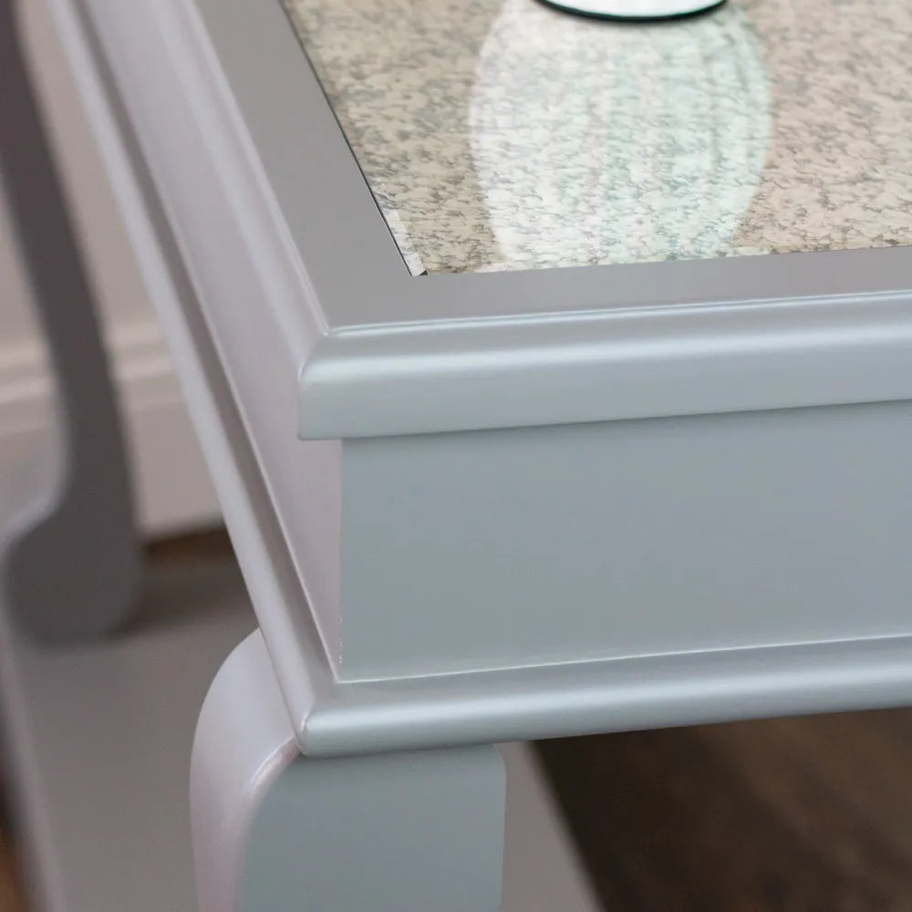 Close-up detail of Tara Lane Scroll Console Table showing mink-colored wooden base with curved leg detail and speckled antique mirror top surface