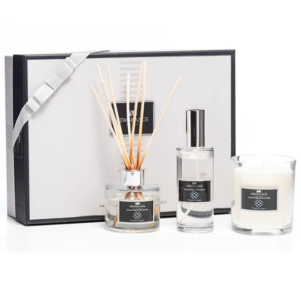 Newgrange Living luxury home fragrance gift set containing black and white gift box with ribbon, reed diffuser with natural wooden sticks, room spray bottle, and white scented candle with black labels