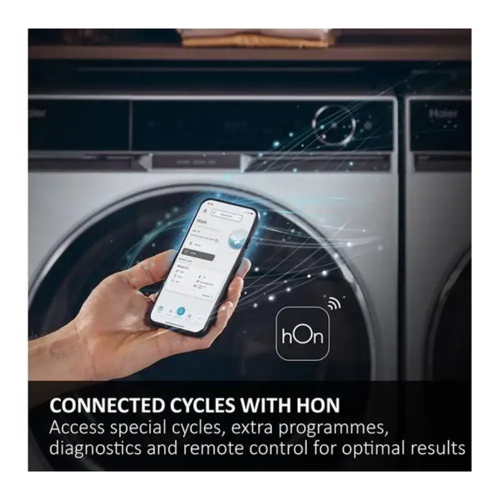 Hand holding smartphone displaying hOn app interface in front of white Haier washing machine with dark drum, showing connected cycles control feature with WiFi connectivity icon