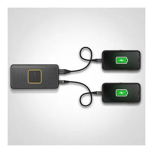 Otterbox 15000mAh black power bank with carbon fiber texture charging two smartphones via USB cables, both phones displaying green battery icons on screens