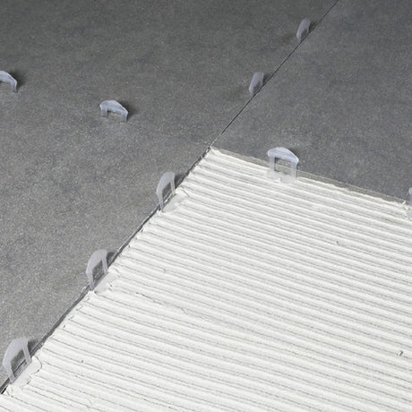 Bihui 2mm wedge levelling tile clips installed on grey floor tiles demonstrating proper spacing and alignment during tile installation