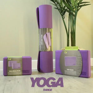 Urban Fitness purple yoga mat set displaying 6mm yoga mat, yoga blocks pair, and yoga brick accessories arranged with potted plant on wooden surface