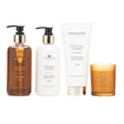 Newgrange Living White Tea and Neroli body care set containing four products including amber glass hand wash bottle, white moisturising body lotion bottle, exfoliating body scrub tube, and amber glass scented candle arranged in a row