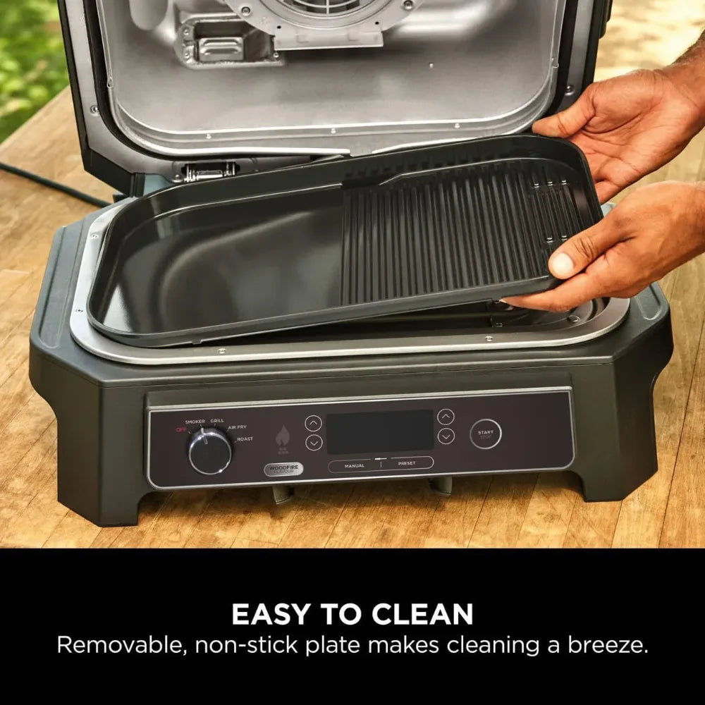 Portable grill with a removable non-stick plate on a wooden surface, emphasizing ease of cleaning.