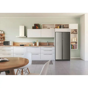 Candy frost free American fridge freezer in stainless steel displayed in a modern kitchen with white cabinetry, wooden countertop and open shelving units against a pale green wall