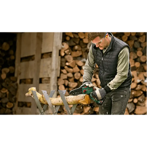 Man using Bosch EasyChain 18V cordless chainsaw to cut log on sawhorse with stacked firewood in background