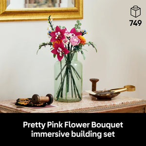 LEGO Pretty Pink Flower Bouquet set 10342 displayed in a clear glass vase with red orchids, pink roses, and white filler flowers on a marble-topped table with gold-framed mirror and vintage sewing accessories, 749 pieces
