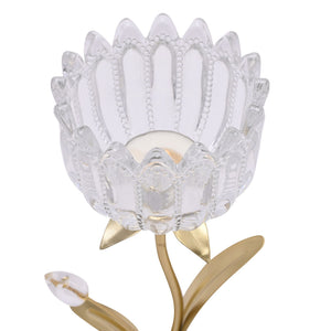 Clear glass flower-shaped candle holder with decorative petal design and beaded details on gold-toned metal stem and base, holding a cream-colored pillar candle