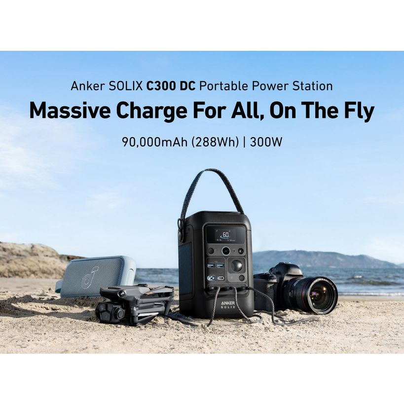 Anker SOLIX C300 DC portable power station displayed on sandy beach with camera, drone, and speaker showing 90,000mAh 288Wh capacity and 300W output