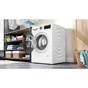 Bosch Series 6 white front-load washing machine with open drum door in modern laundry room setting, surrounded by black shelving with folded towels and woven storage baskets