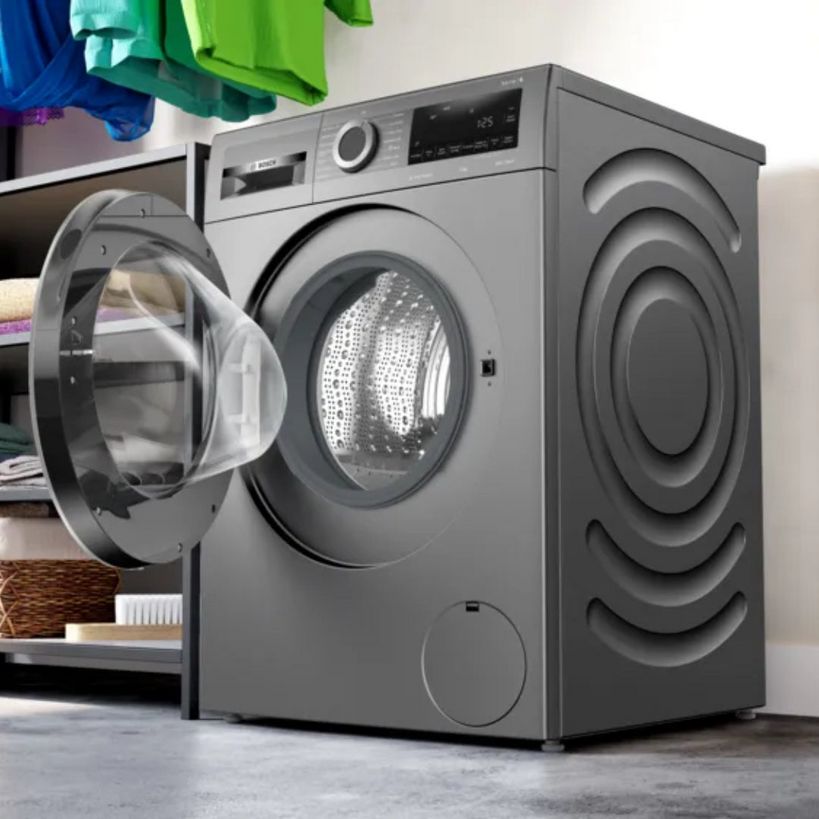 BOSCH Series 6 graphite grey front-load washing machine with open door showing stainless steel drum, 9kg capacity, 1400 spin, displayed in laundry room setting with colorful towels and storage shelves