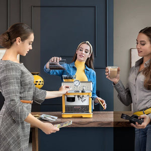 Three women demonstrating the DeLonghi La Specialista Arte manual bean to cup coffee machine in yellow and black, with one pouring liquid into the machine, another holding a cup of coffee, and a third holding the instruction manual, set in a modern kitchen with dark blue cabinetry