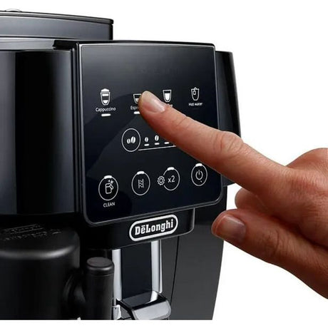 Hand pointing at touchscreen display on DeLonghi Magnifica Start black automatic coffee machine showing cappuccino, espresso, and hot water beverage options with control buttons