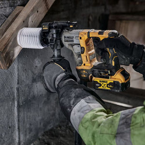 DeWalt DCH172P2 18V XR SDS Plus rotary hammer in yellow and black being used by worker in green jacket to drill into concrete wall, with battery pack visible