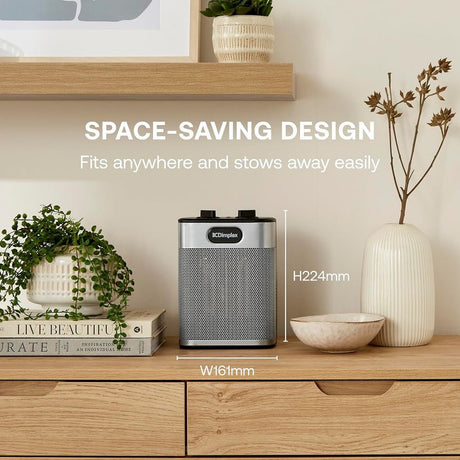 Dimplex 2000W ceramic fan heater in black and silver displayed on wooden desk shelf with dimensions H224mm W161mm, surrounded by potted plants and decorative items, demonstrating compact space-saving design
