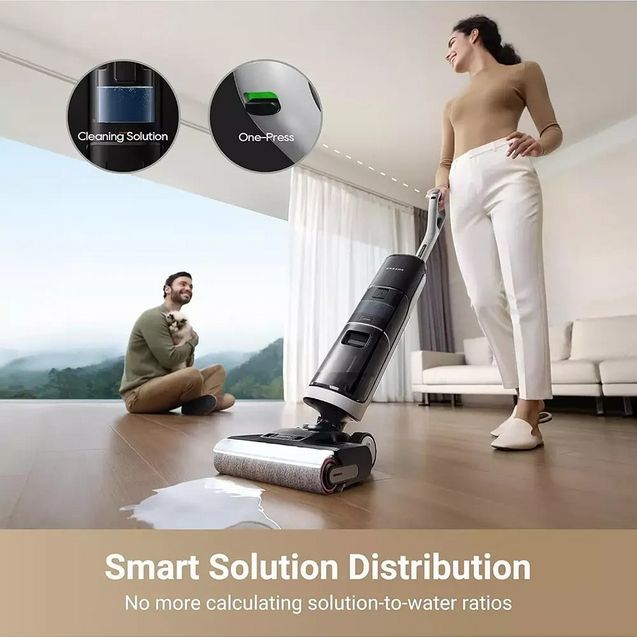 Dreame H14 Pro wet and dry vacuum cleaner with smart solution distribution feature being used on wooden floor by woman in white pants, showing one-press and cleaning solution capabilities with man sitting in background near large window