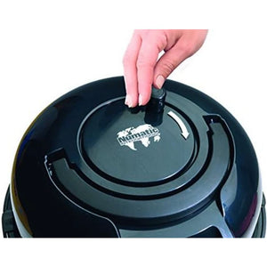 Hand lifting the dust collection lid on a Numatic Hetty pink and black upright vacuum cleaner showing the circular collection chamber and branded lid