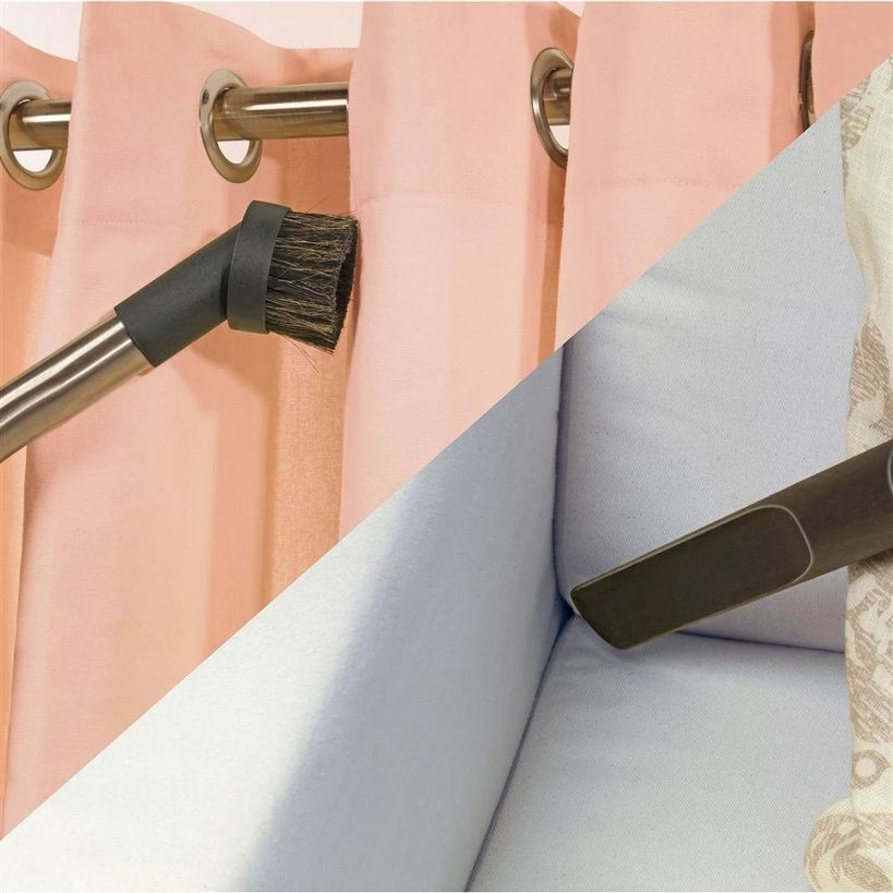 Close-up of pink curtains with brass grommet eyelets and metal rod, showing white upholstered furniture edge and cleaning brush attachment detail