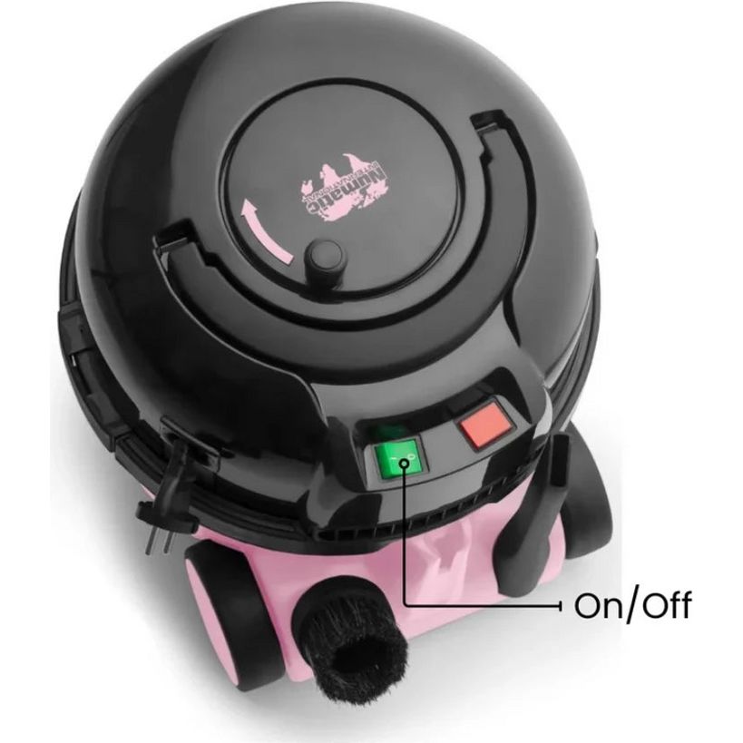 Top-down view of Hetty vacuum cleaner in pink and black with grey dome top, showing on/off power button with green indicator light and red button, featuring distinctive round design and black brush head detail