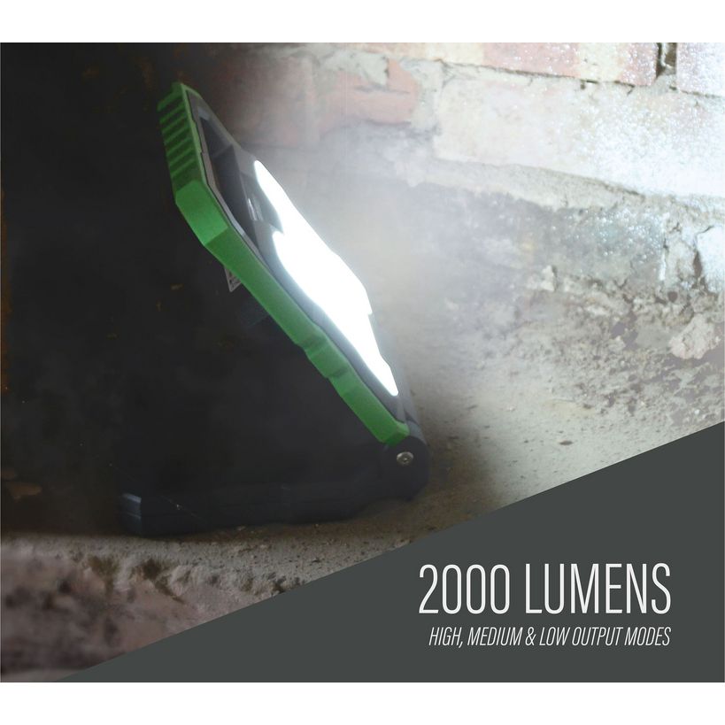 Lighthouse 2000 lumens rechargeable worklight with green and black body illuminating a concrete surface, demonstrating high brightness output for work applications