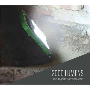 Lighthouse 2000 lumens rechargeable worklight with green and black body illuminating a concrete surface, demonstrating high brightness output for work applications