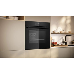 Neff N30 black pyrolytic single built-in oven integrated into beige kitchen cabinetry with open shelving displaying kitchenware and a black tap