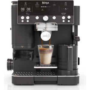 Ninja Luxe Café Premier Series black automatic coffee machine with digital display dispensing a layered cappuccino into a glass cup, featuring multiple control dials and a milk frother on the right side