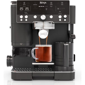 Ninja Luxe Café Premier Series black automatic coffee machine with digital display showing 25-25, dispensing espresso into a glass cup, featuring multiple control knobs and buttons, stainless steel group head, and integrated milk frother on the right side