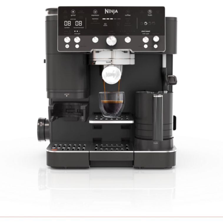 Ninja Luxe Café Premier Series black automatic coffee machine with digital display showing espresso being dispensed into a glass cup, featuring multiple control dials and a built-in milk frother on a white background