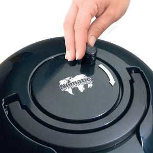 Close-up of a hand opening the black cylindrical dust container lid of a Numatic Henry vacuum cleaner, showing the white Numatic International logo on the dark gray collection chamber
