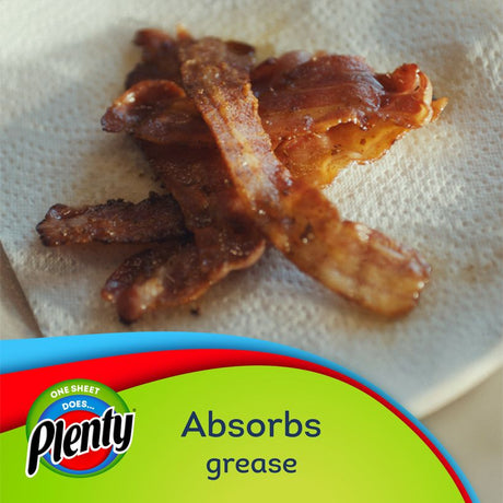 Crispy bacon strips on white Plenty paper towel demonstrating grease absorption capability with green and red Plenty brand packaging visible below