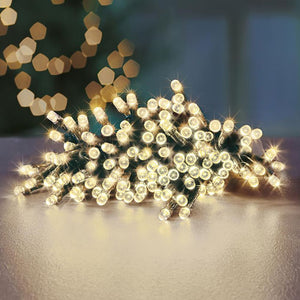 Battery-operated LED fairy lights with 24 warm white bulbs coiled on a light surface, featuring a timer function, displayed against a blurred background with decorative bokeh lights