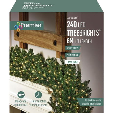 Premier 240 LED Treebrights warm white multi-action fairy lights with 6m lit length and green cable draped over evergreen garland on white mantelpiece with wooden beam, showing product packaging details including timer function and indoor outdoor use specifications