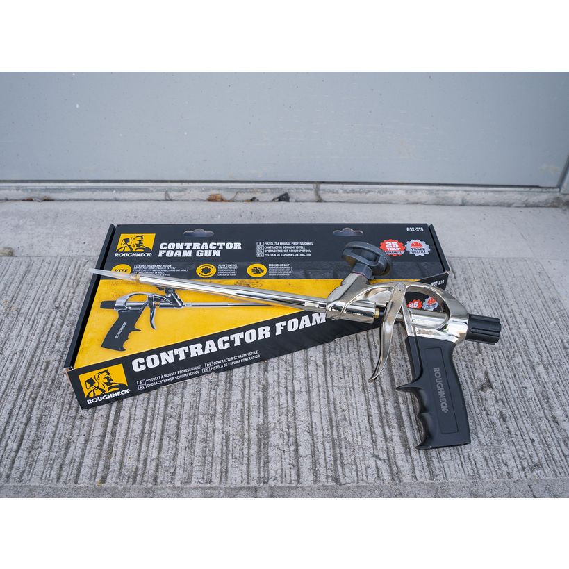 Roughneck Contractor Foam Gun with yellow and black packaging displayed on concrete surface showing the chrome and black metal applicator gun with black handle grip and product box