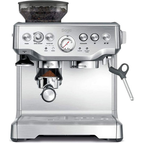 Sage The Barista Express espresso machine in brushed stainless steel with integrated grinder, featuring a bean hopper on top, control panel with multiple buttons and pressure gauge, portafilter with grounds, and steam wand on front